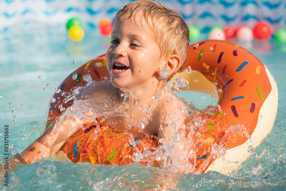 Happy little boy playing with colorful inflatable ring in outdoor swimming  pool on hot summer day. Kids learn to swim. Child water toys.close up.  Stock Photo | Adobe Stock