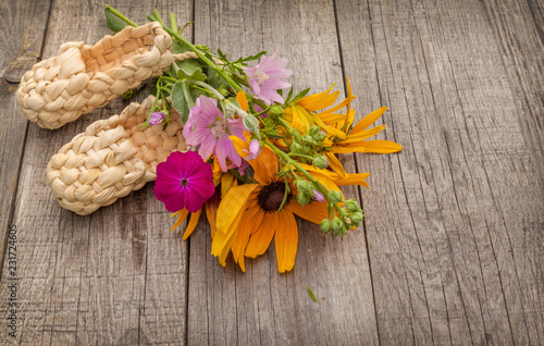 Fototapeta Naklejka Na Ścianę i Meble -  Summer still life with rudbeckia and straw bast shoes