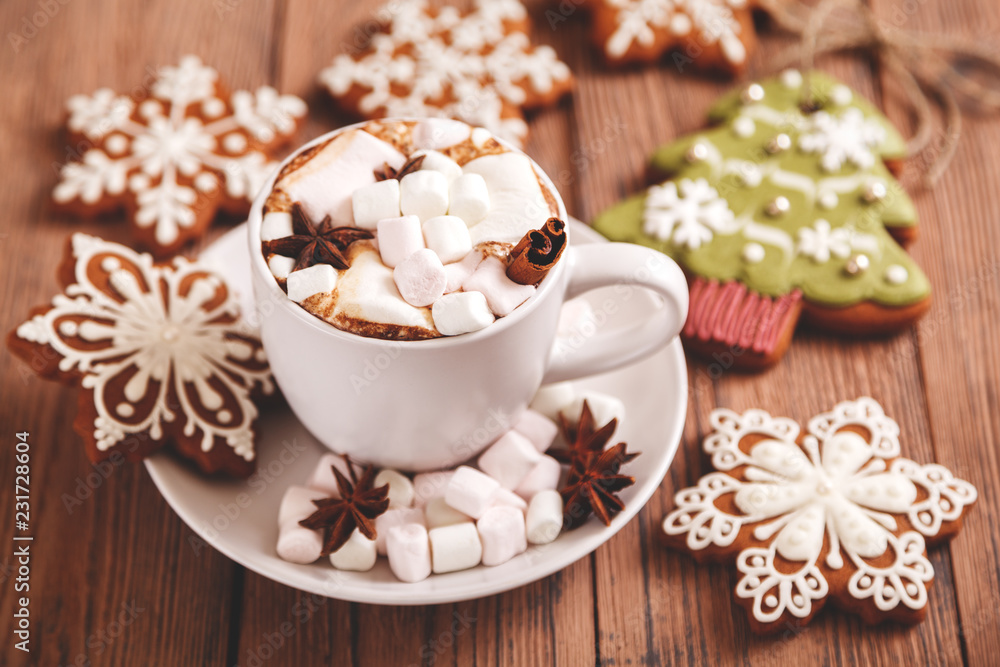 Christmas or new year background. A Cup of festive hot chocolate or cocoa with marshmallows and traditional handmade gingerbread on the table. The concept of advertising cocoa drink. Christmas or new year background. A Cup of festive hot chocolate or cocoa with marshmallows and traditional handmade gingerbread on the table. The concept of advertising cocoa drink.