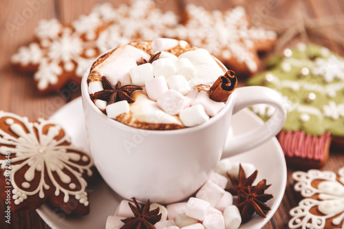 Christmas or new year background. A Cup of festive hot chocolate or cocoa with marshmallows and traditional handmade gingerbread on the table. The concept of advertising cocoa drink. 