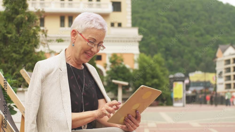 An elegant cheerful woman is surfing the Net in the luxury hotel. Lady browsing the Net in the street. An elegant cheerful woman is surfing the Net in the luxury hotel. Lady browsing the Net in the street.