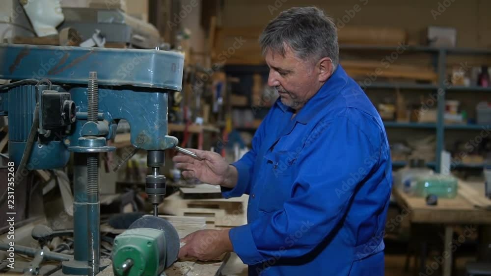 employee drills the item in the workshop with the help of a drilling press employee drills the item in the workshop with the help of a drilling press
