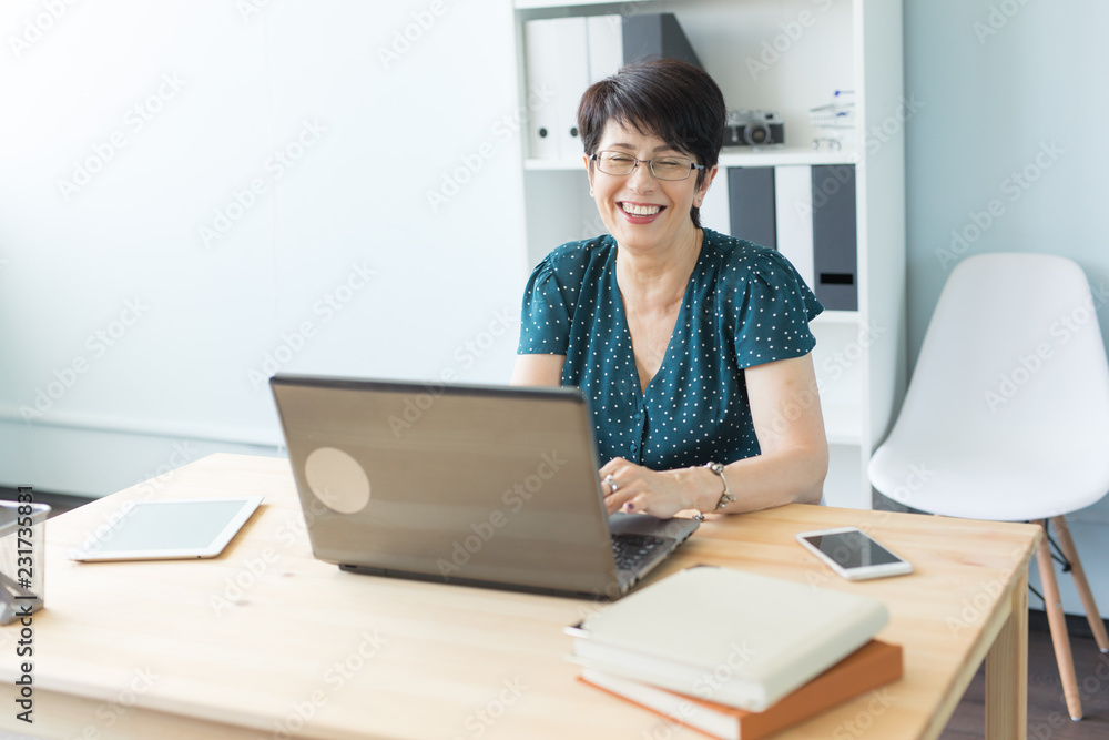 Business people and technology concept - Middle-aged woman working at laptop Business people and technology concept - Middle-aged woman working at laptop