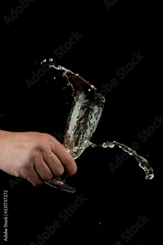 hand is holding a glass of champagne, splashing it around