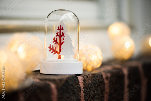 Christmas snow globe with trees and lights on a window, brick wall. Copy space