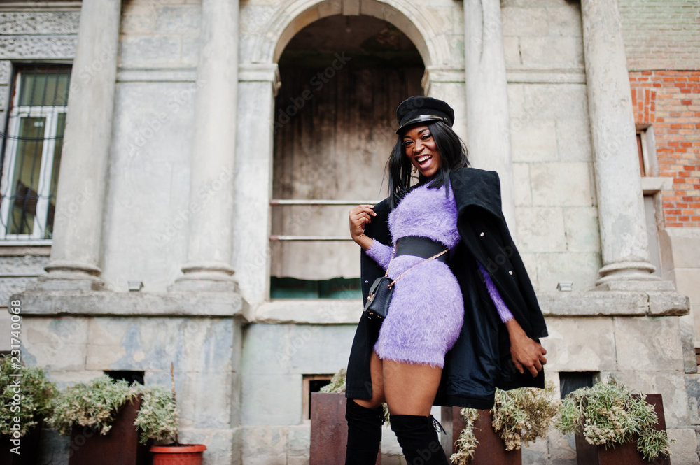 African american woman at violet dress and cap posed outdoor.