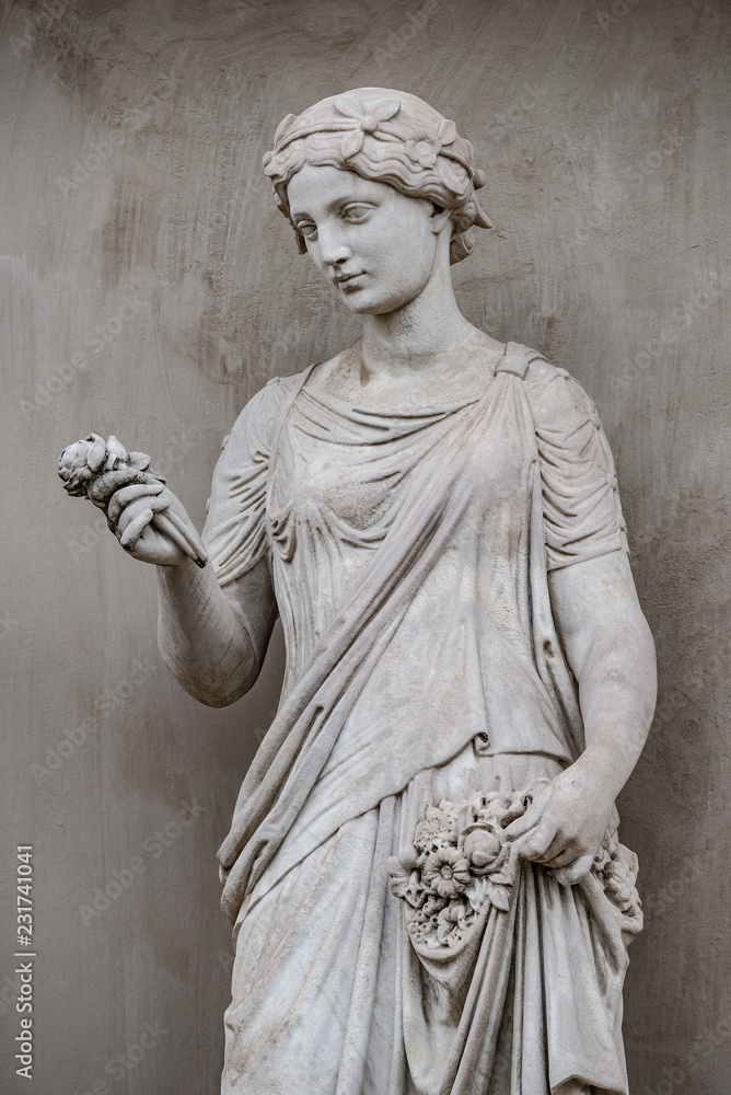 Fototapeta premium Antyczny posąg zmysłowej kobiety epoki greckiego renesansu z kwiatem, Poczdam, Niemcy, szczegóły, zbliżenie