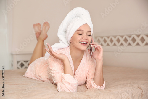 Beautiful woman with towel on head talking on phone in bedroom at home