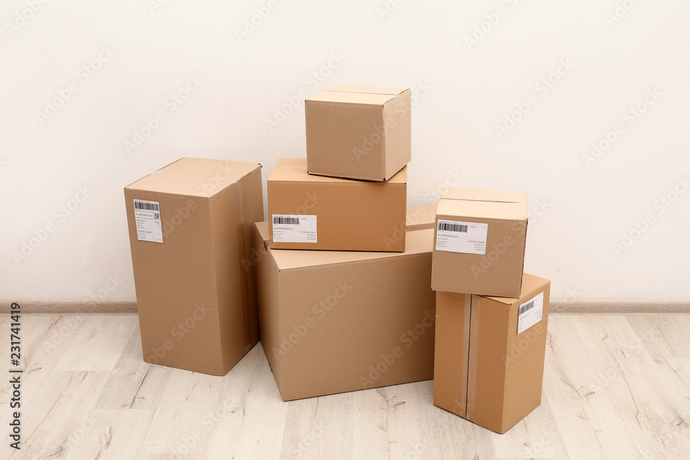Stacked parcel boxes on floor against light wall Stacked parcel boxes on floor against light wall