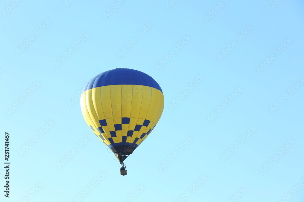 Fototapeta premium Colorful hot air balloon flying in blue sky. Space for text