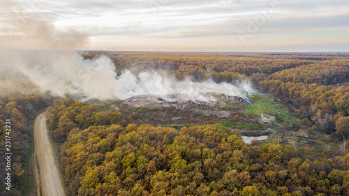 Aerial view of illegal landfill in the forest. Waste incineration  environmental issue  heavy junk smoke. Environmental pollution aft.