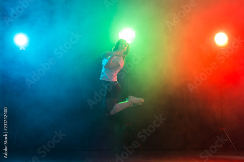 Canvas Print Dancing, sport, jazz funk and people concept - young woman jump in the darkness
