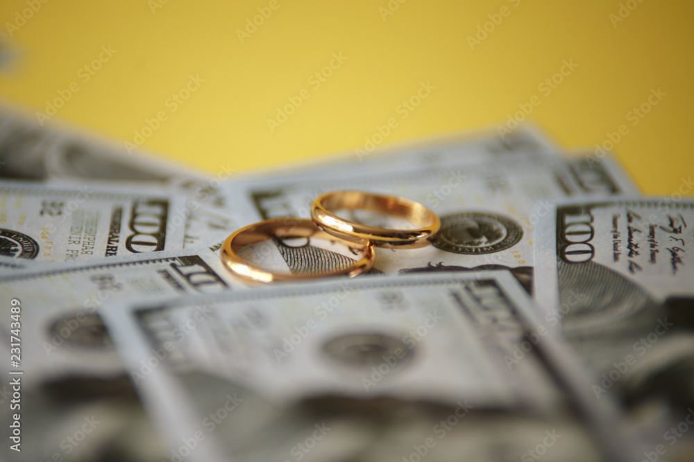 Golden wedding rings on dollars bill background. Divorce or infidelity concept Golden wedding rings on dollars bill background. Divorce or infidelity concept