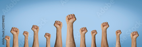 Hands raised up and clenched in a fist on a blue background. Concept of unity of the people, revolution, revolt, riot. Banner