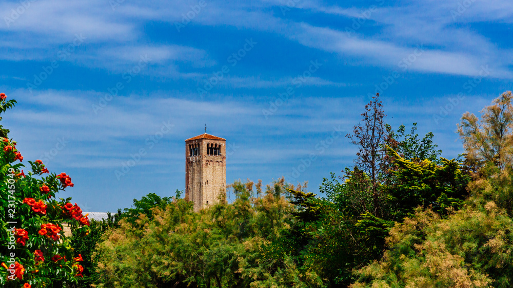 Naklejka premium Bell tower of Torcello Cathedral over trees on the island of Torcello, Venice, Italy