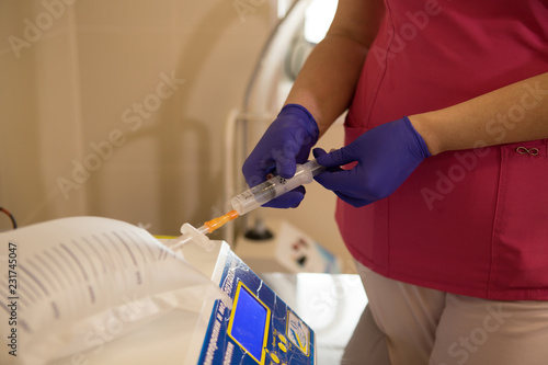 Cosmetologist injecting ozone to chin. Patient is sitting in chair with closed eyes. This therapy is purposed to increase oxygen in a body. photo