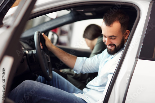 Adult couple choosing new car in showroom