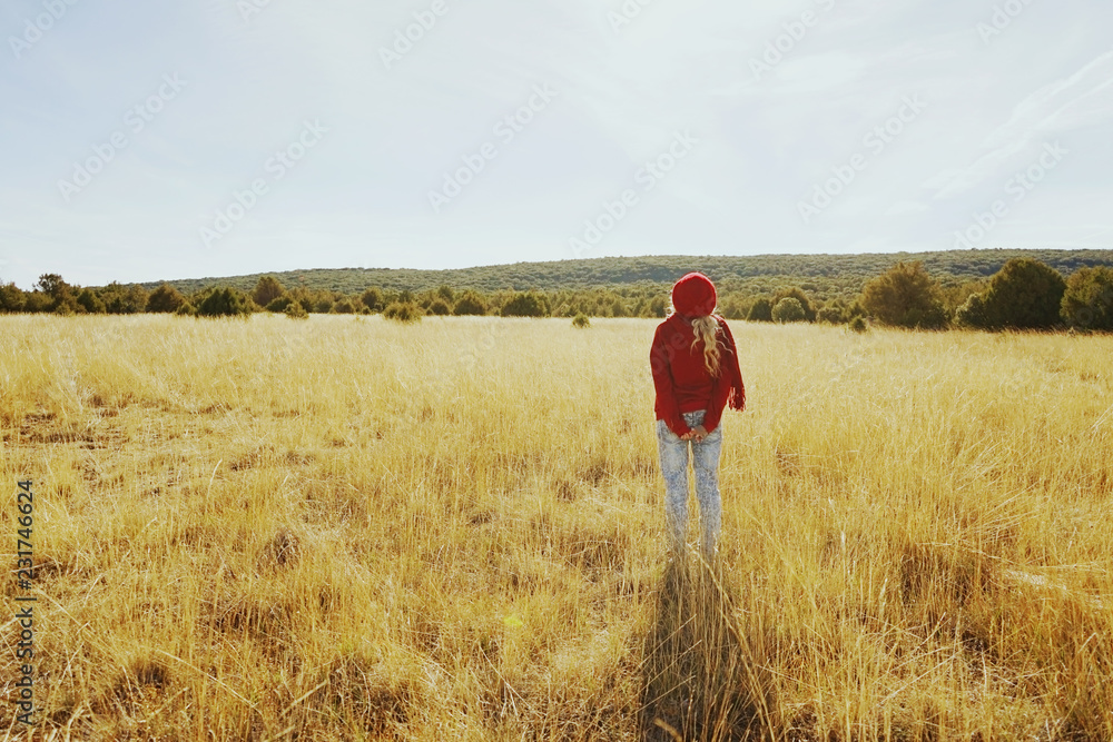Back view of a young woman in nature in a sunny autumn day Back view of a young woman in nature in a sunny autumn day