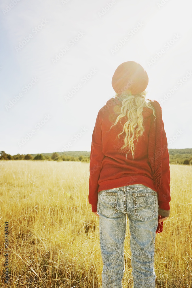 Back view of a young woman in nature in a sunny autumn day Back view of a young woman in nature in a sunny autumn day