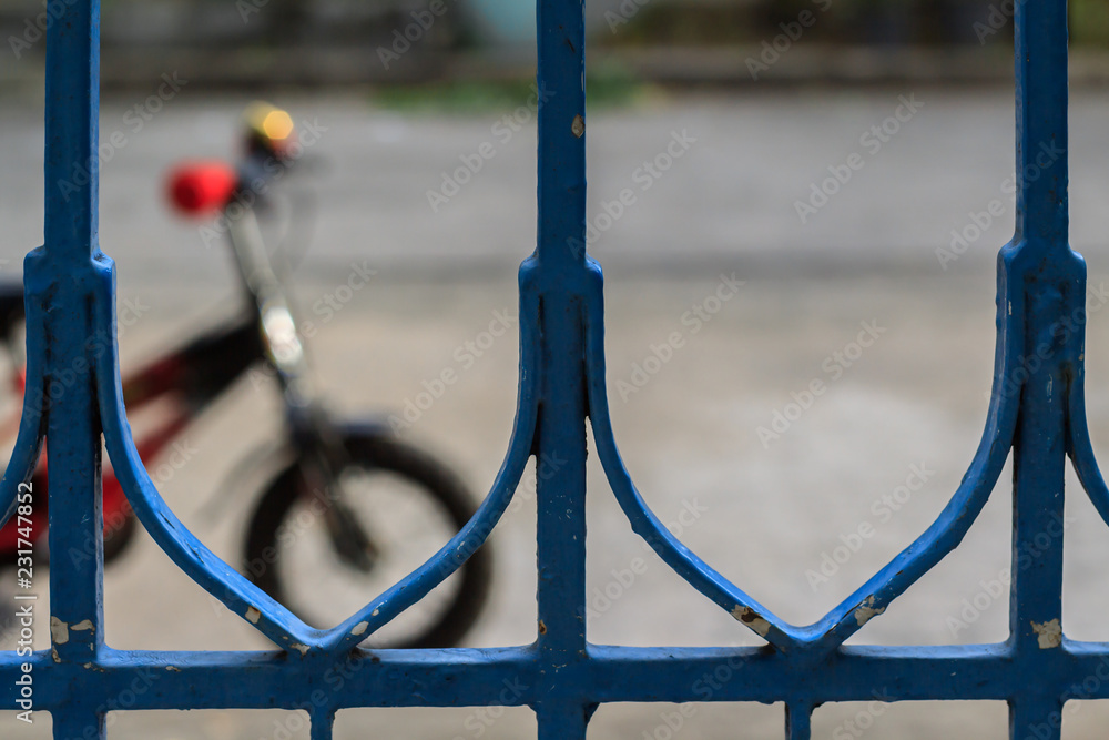 Little boy age 4 years old forgot his red bicycle in front of home and blue fence, Blurred mini bike are forgotten outside the house, Selective focus and copy space for robbery or discipline concept Little boy age 4 years old forgot his red bicycle in front of home and blue fence, Blurred mini bike are forgotten outside the house, Selective focus and copy space for robbery or discipline concept