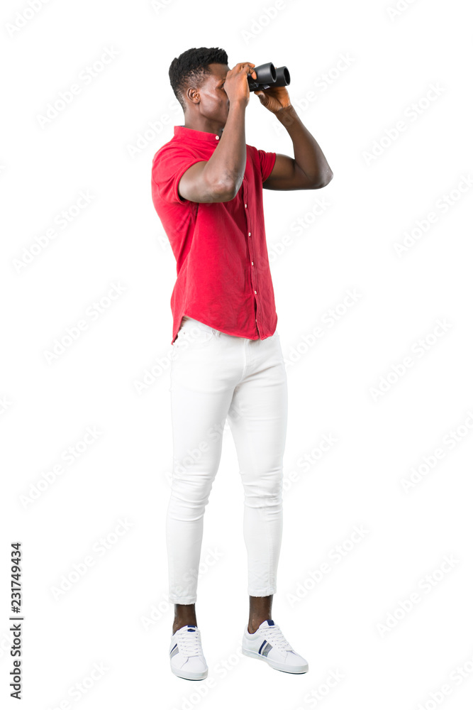 Full body of Young african american man and looking for something in the distance with binoculars on white background Full body of Young african american man and looking for something in the distance with binoculars on white background