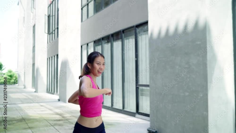 Slow motion - Healthy beautiful young Asian Athlete women sports clothing legs warming and stretching her arms to ready for running on street in urban city. Lifestyle active exercise in city concept. Slow motion - Healthy beautiful young Asian Athlete women sports clothing legs warming and stretching her arms to ready for running on street in urban city. Lifestyle active exercise in city concept.