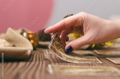 Tarot cards and hands of fortune teller on wooden table background.