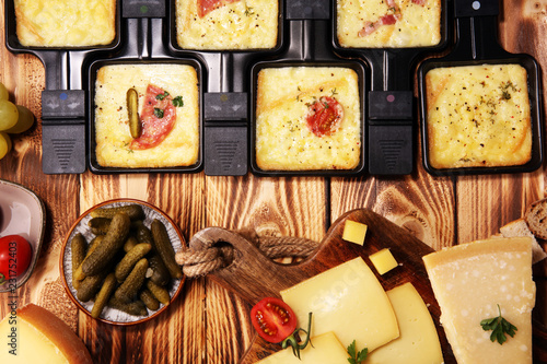 Delicious traditional Swiss melted raclette cheese served in individual skillets with salami.