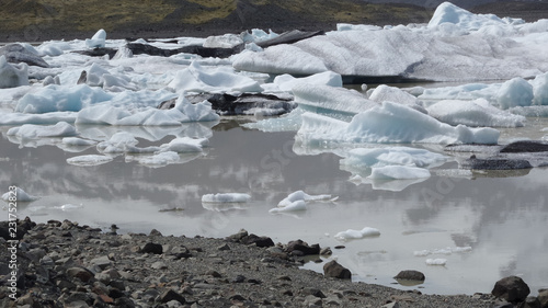 Eisberge auf einem Fluß in Island hinter schwarzem Felsufer 