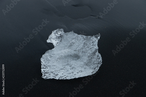 Eiskristall mit Lufteinschlüssen auf schwarzem Sandstrand in Island