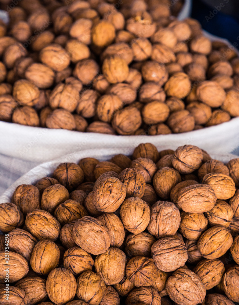 Many walnuts lie on the market and in the store. Open and peeled nuts are full of vitamins, a fresh and healthy snack for vegetarians. Shelled nuts in curved forms. Big plates on the market. Many walnuts lie on the market and in the store. Open and peeled nuts are full of vitamins, a fresh and healthy snack for vegetarians. Shelled nuts in curved forms. Big plates on the market.