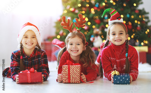 happy children girls with christmas gifts near tree in  morning photo