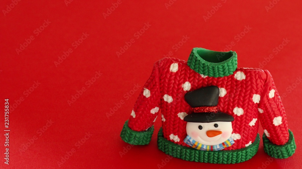red sweater with green collar and sleeve cuffs white snowflakes and snowman with black hat and carrot nose isolated on a festive red background