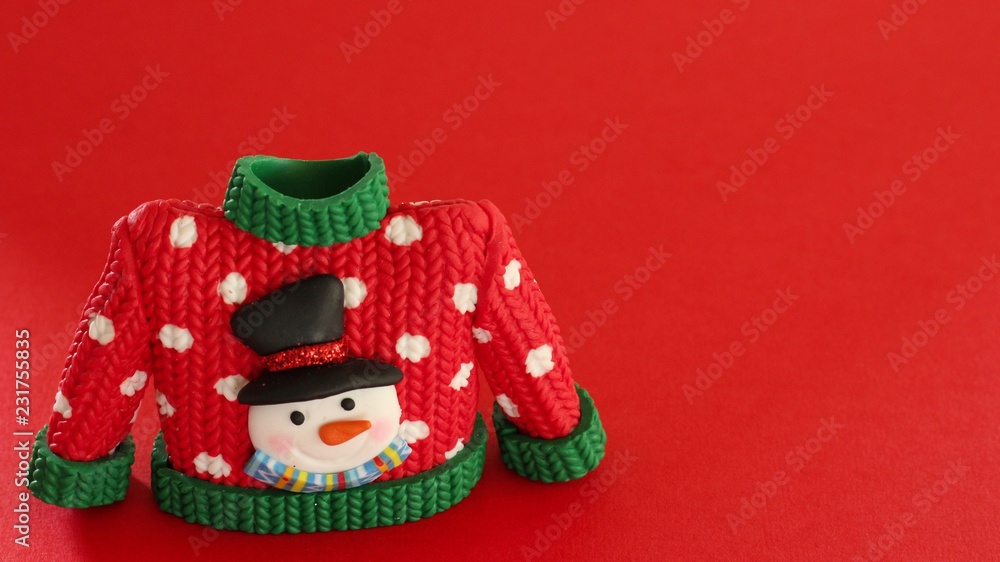 red sweater with green collar and sleeve cuffs white snowflakes and snowman with black hat and carrot nose isolated on festive red background with writing space