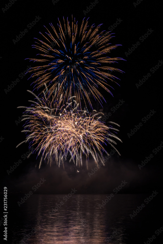 Big gold and blue stars from fireworks over Brno's Dam with lake reflection Big gold and blue stars from fireworks over Brno's Dam with lake reflection