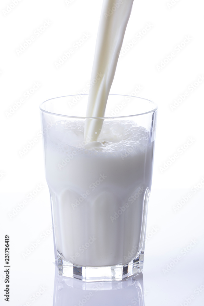 pouring a glass of milk creating splash on a white background pouring a glass of milk creating splash on a white background