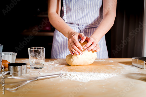 Making dough by female hands on wooden table
