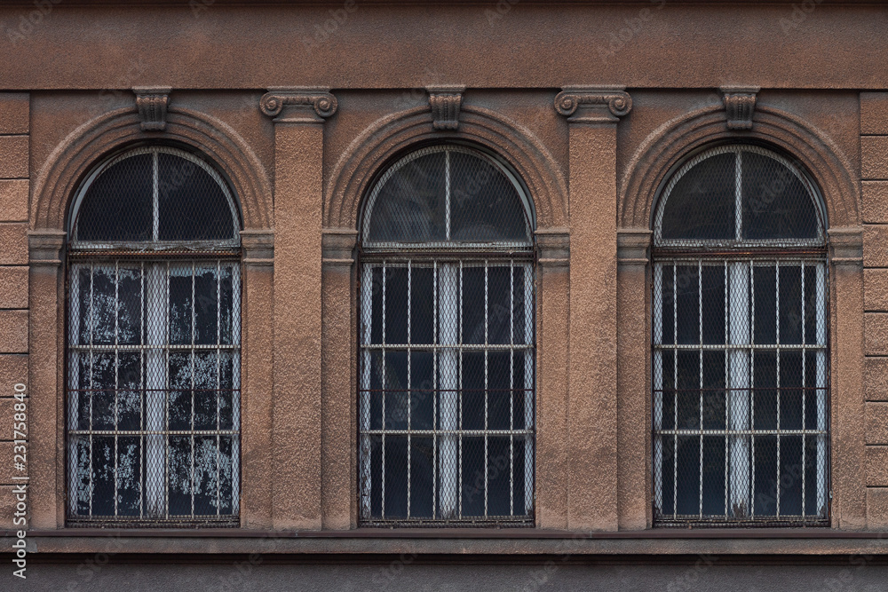 Three arched windows on an old ornate facade