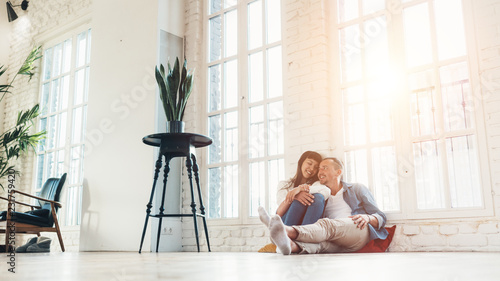 Lovely couple sitting together in big loft living room. Romantic relationship and domestic life