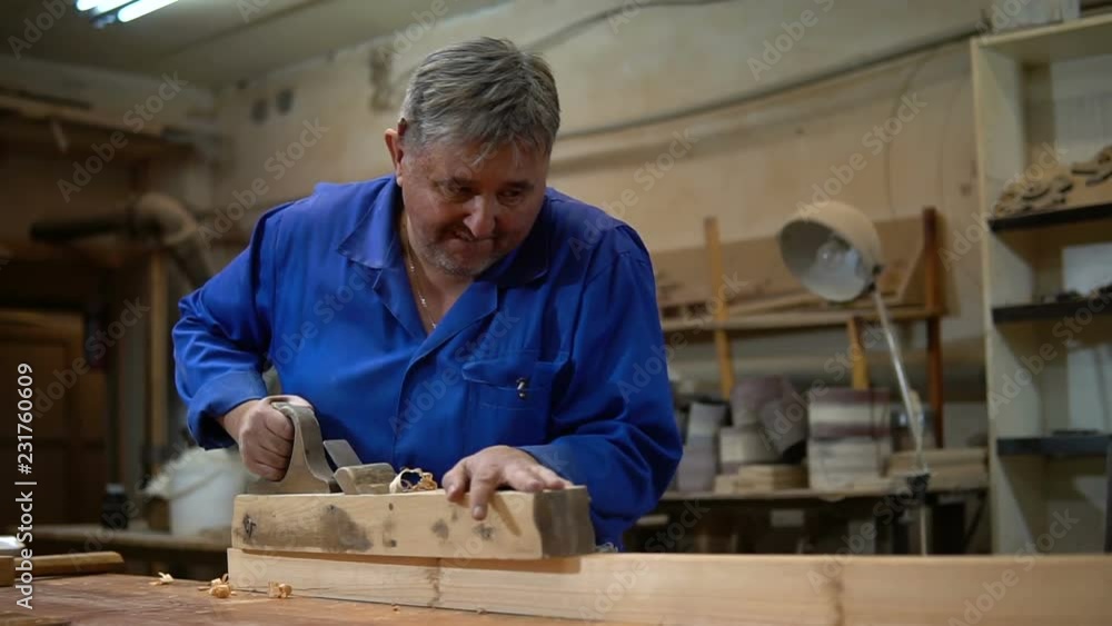 carpenter working in the Studio, worker planing a tree with a planer carpenter working in the Studio, worker planing a tree with a planer