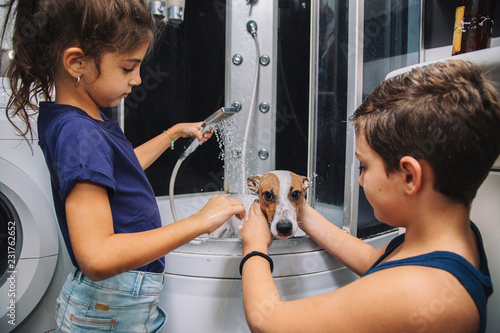 children ,boz and girl, bath his dog at home 