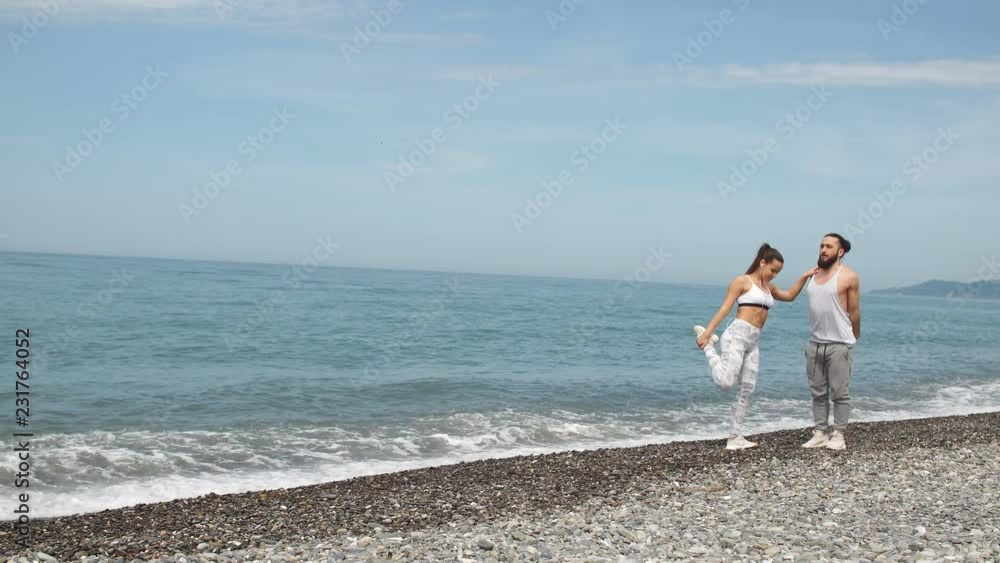 Fitness woman and muscular strong man exercising and stretching arms and legs on beautiful beach at evening time, outdoors. Fitness woman and muscular strong man exercising and stretching arms and legs on beautiful beach at evening time, outdoors.