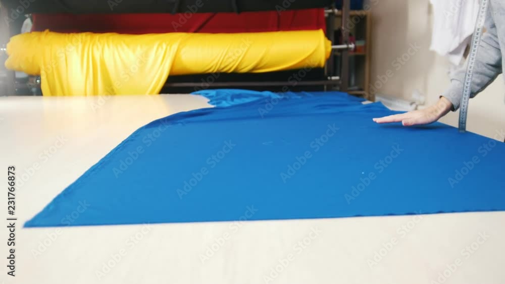 Worker at the factory lay cloth on the table Worker at the factory lay cloth on the table