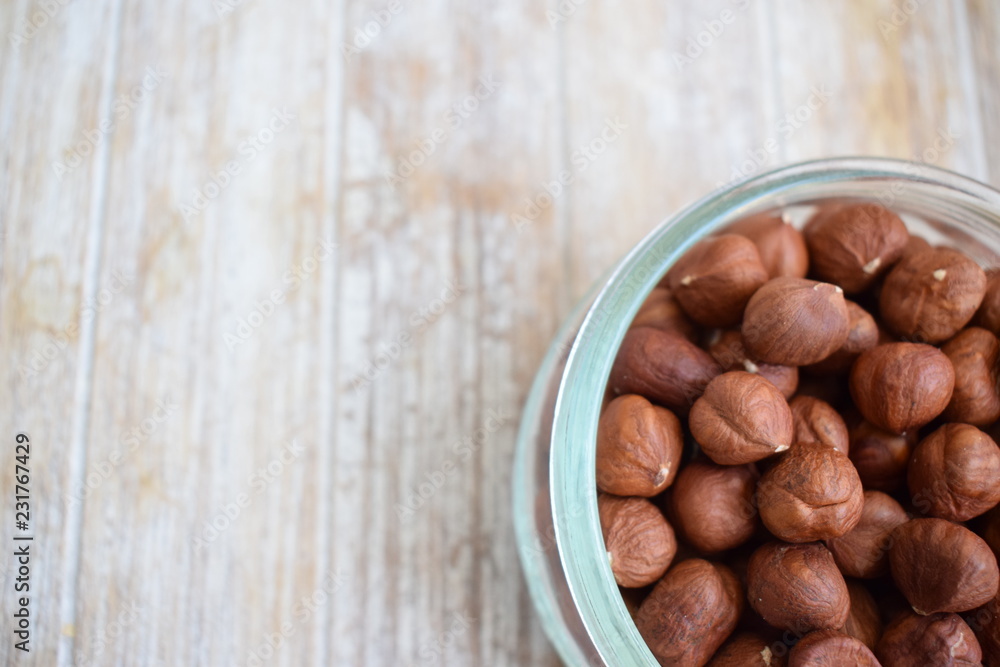 Obraz premium Hazelnuts in a glass jar in the background of the tree. Copy space.