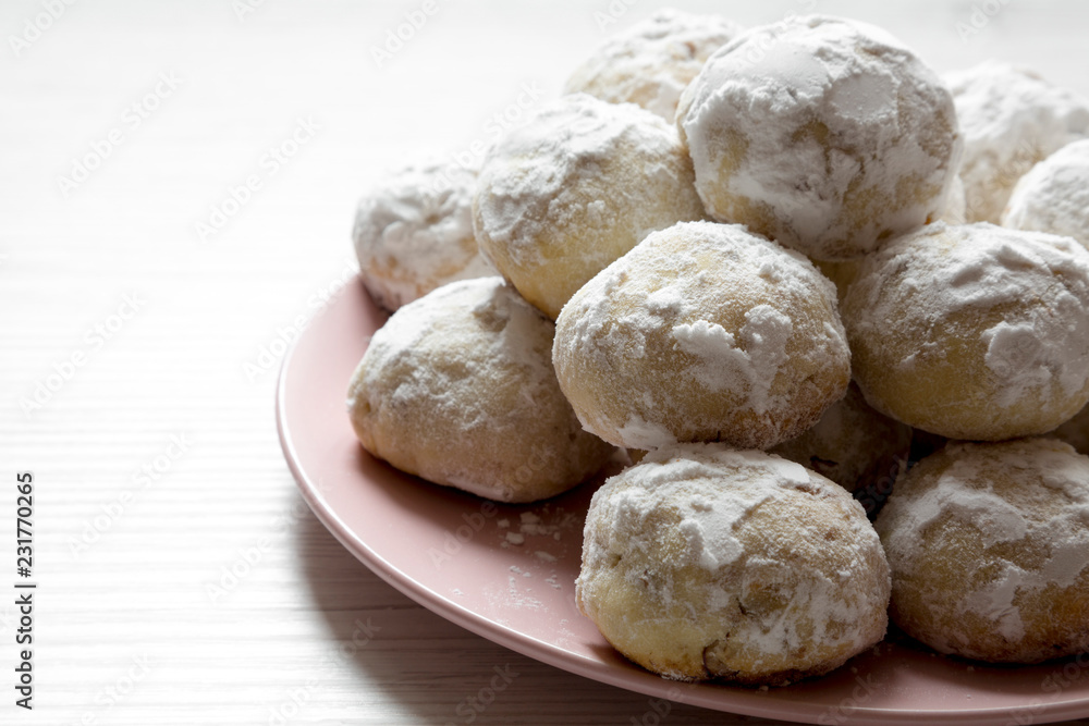 Homemade white mexican wedding cookies on pink plate over white wooden background, side view. Homemade white mexican wedding cookies on pink plate over white wooden background, side view.