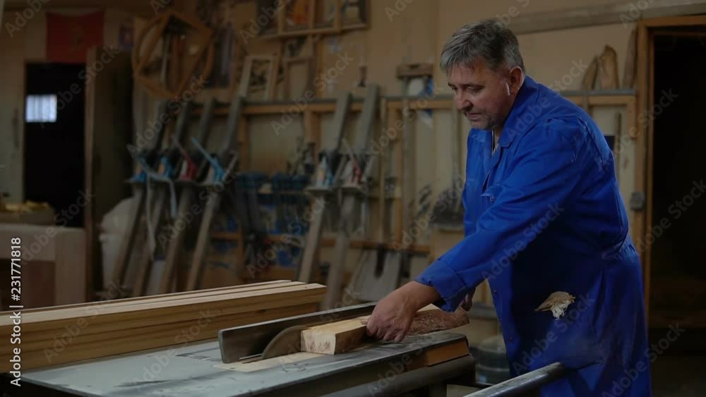 Carpenter at work at his workshop, wood processing on a woodworking machine Carpenter at work at his workshop, wood processing on a woodworking machine