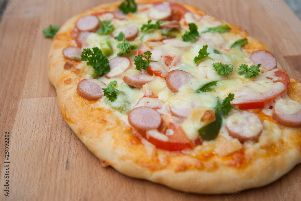 Fresh baked homemade pizza with cheese and tomatoes over wooden cutting board. Rustic style.