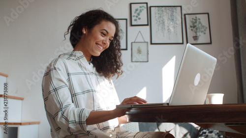 Photography Charming young woman typing on laptop computer at home.