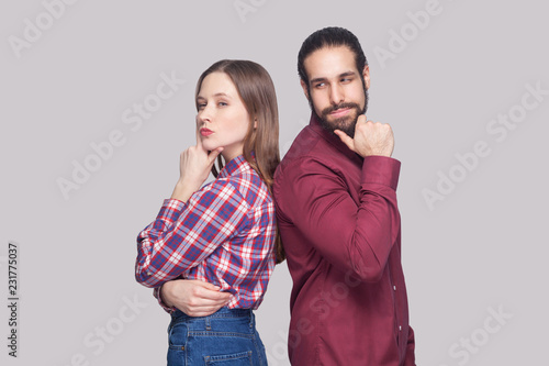 Profile side view portrait of thoughtful bearded man and woman in casual style standing touching chin and thinking with serious face. indoor studio shot, isolated on gray background.