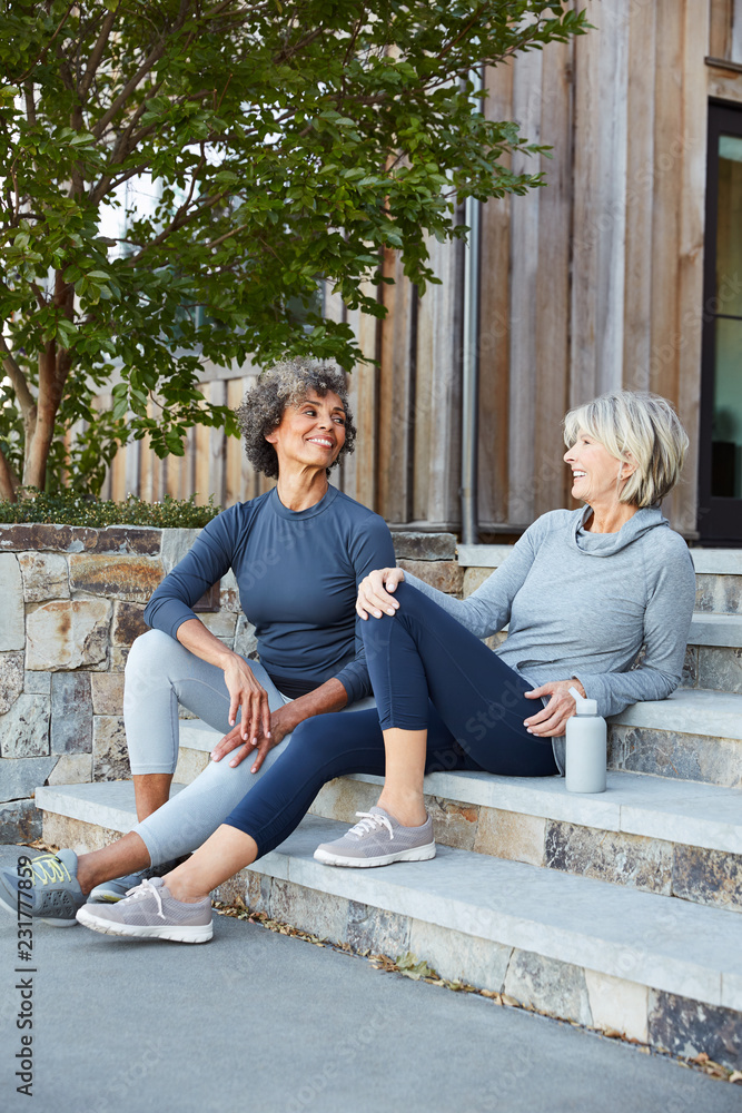 Senior women friends relaxing and talking after a run together Senior women friends relaxing and talking after a run together